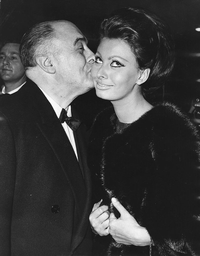 Italian film producer Carlo Ponti kisses his wife, actress Sophia Loren after she received the first Alexander Korda award, naming her 'International Star of the Year', at the world premiere of her new film